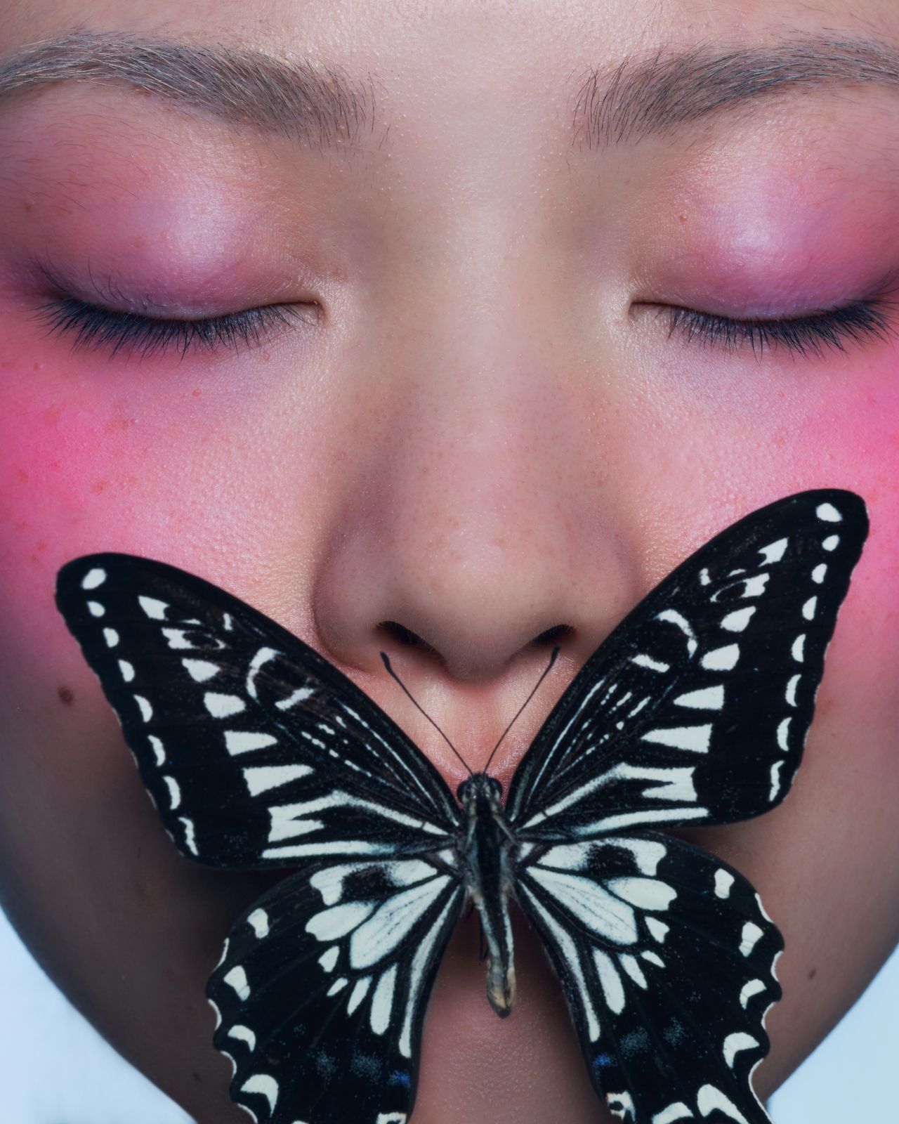 Retrato editorial con una mariposa posada sobre el rostro, símbolo de transformación y delicadeza